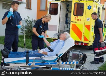 Emergency team examining injured senior patient lying on stretcher outdoors