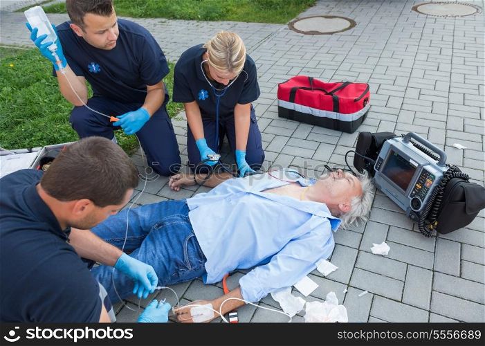 Emergency team giving firstaid to injured elderly patient on street