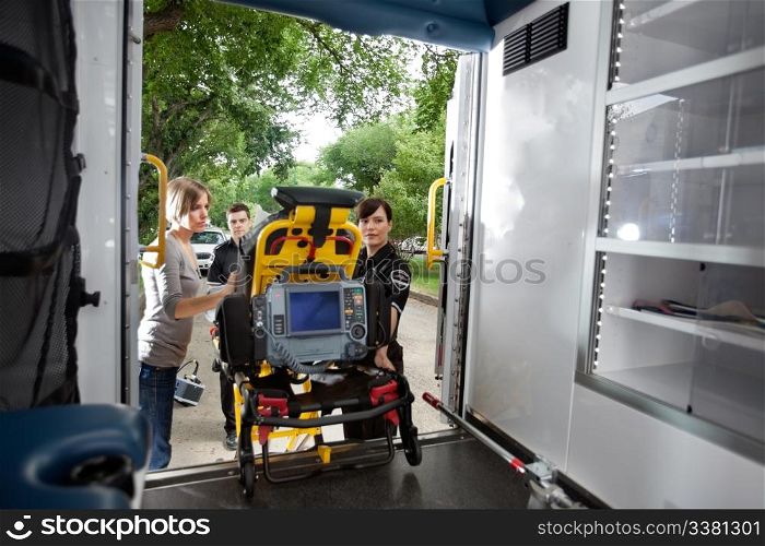 Emergency team loading patient in ambulance, caregiver at side