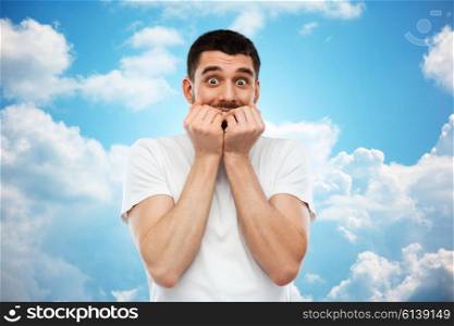 emotion, advertisement and people concept - scared man in white t-shirt over blue sky and clouds background