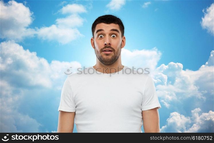 emotion, advertisement and people concept - scared man in white t-shirt over blue sky and clouds background