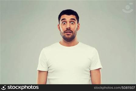 emotion, advertisement and people concept - scared man in white t-shirt over gray background. scared man in white t-shirt over gray background