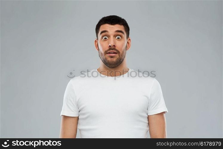 emotion, advertisement and people concept - scared man in white t-shirt over gray background