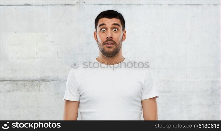 emotion, advertisement and people concept - scared man in white t-shirt over gray wall background