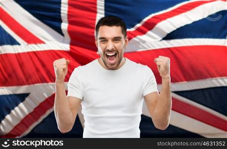 emotion, aggression, patriotism, gesture and people concept - angry young man showing fists and shouting over brittish flag