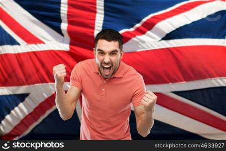 emotion, aggression, patriotism, gesture and people concept - angry young man showing fists and shouting over brittish flag