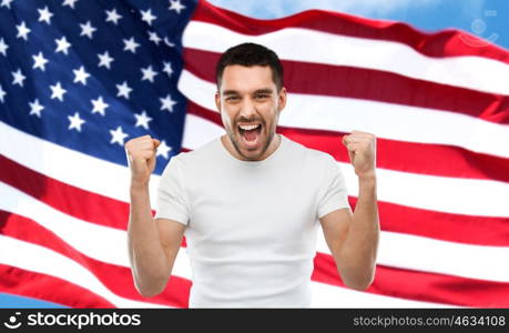 emotion, aggression, patriotism, gesture and people concept - angry young man showing fists and shouting over american flag