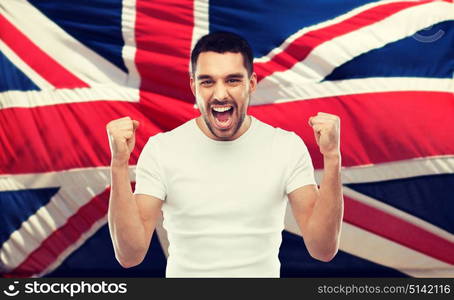 emotion, aggression, patriotism, gesture and people concept - angry young man showing fists and shouting over brittish flag. angry man showing fists over brittish flag