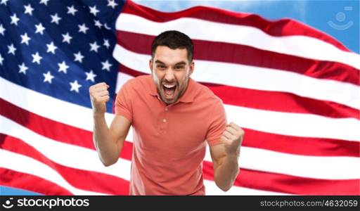 emotion, aggression, patriotism, gesture and people concept - angry young man showing fists over american flag