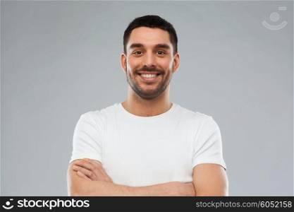 emotion and people concept - happy smiling young man with crossed arms over gray background. smiling man with crossed arms over gray background