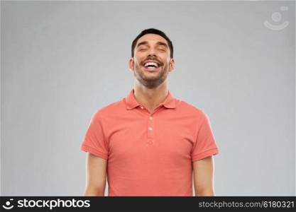 emotion and people concept - laughing man in polo t-shirt over gray background. laughing man over gray background