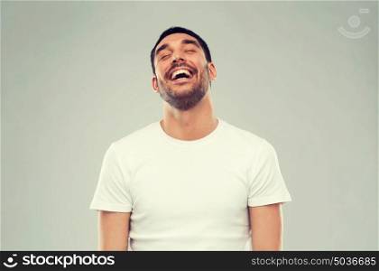 emotion and people concept - laughing man over gray background. laughing man over gray background