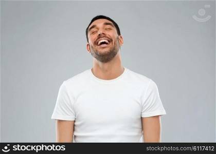 emotion and people concept - laughing man over gray background. laughing man over gray background