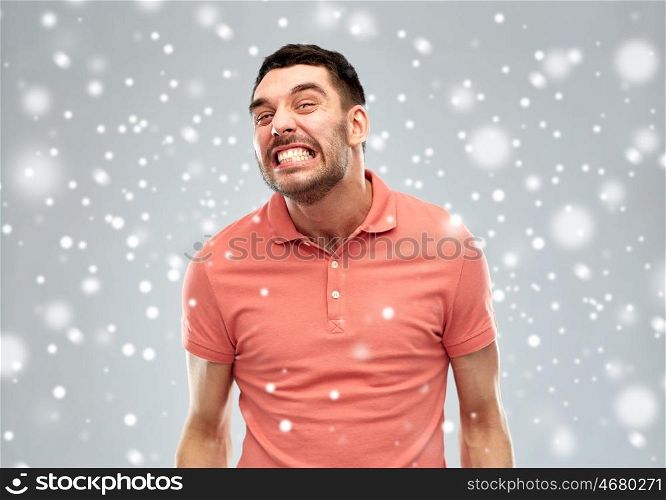 emotion, anger, winter, christmas and people concept - angry man over snow on gray background