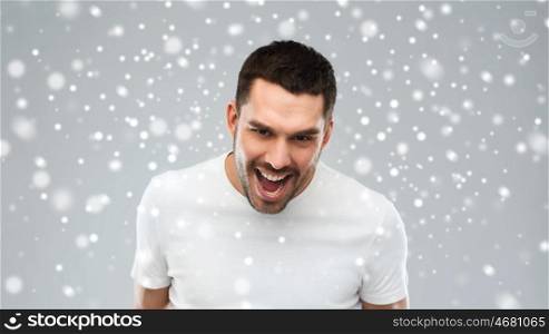 emotion, anger, winter, christmas and people concept - angry man over snow on gray background