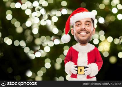 emotion, christmas and winter holiday concept - happy smiling young man in santa claus costume over festive lights on dark green background (funny cartoon style character with big head). smiling man in santa costume over christmas tree