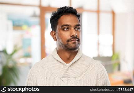 emotion, expression and people concept - indian man in knitted woolen sweater over office background. indian man in sweater over office background