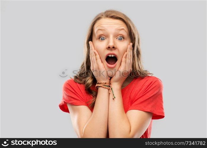 emotion, expression and people concept - shocked or scared teenage girl with open mouth in red t-shirt over grey background. shocked or scared teenage girl in red t-shirt