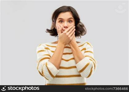 emotion, expression and people concept - shocked young woman in striped pullover covering her mouth by hands over grey background. shocked young woman covering her mouth by hands