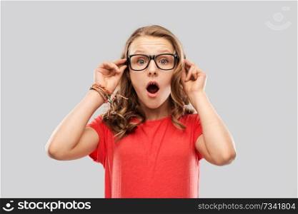 emotion, expression and people concept - surprised or shocked teenage girl with open mouth in glasses over grey background. surprised or shocked teenage girl in glasses