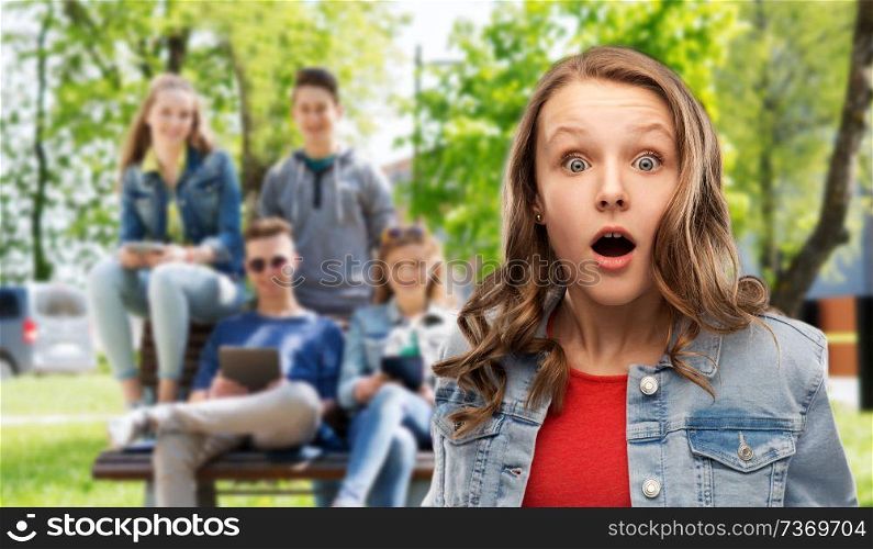 emotion, expression and people concept - surprised or shocked teenage girl with open mouth over group of friends background. surprised or shocked teenage girl over friends