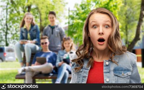 emotion, expression and people concept - surprised or shocked teenage girl with open mouth over group of friends background. surprised or shocked teenage girl over friends