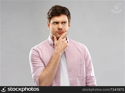 emotion, expression and people concept - thoughtful young man over grey background. young man thinking and looking up