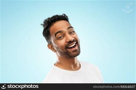 emotion, expression and people concept - young laughing indian man over blue background. young laughing indian man over blue background