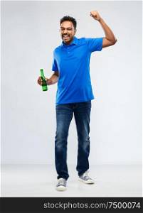 emotion, expression and success concept - happy indian man or sports fan beer bottle celebrating victory over grey background. male fan with beer bottle celebrating victory