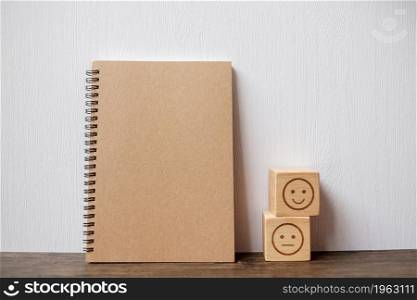emotion face block and notebook on table. Emoticon for customer review, satisfaction, mood, mental health and feedback concept