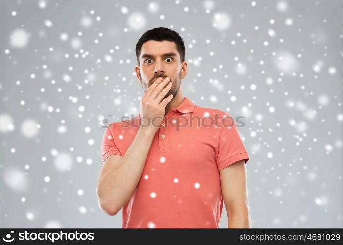 emotion, fear, winter, christmas and people concept - scared man in polo t-shirt over snow on gray background