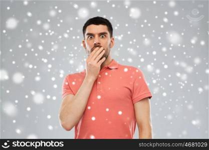 emotion, fear, winter, christmas and people concept - scared man in polo t-shirt over snow on gray background