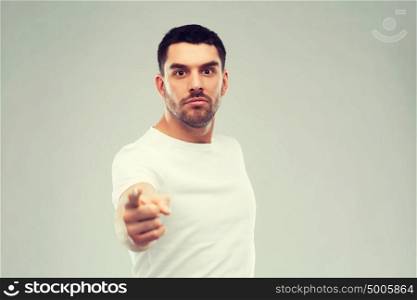 emotion, gesture and people concept - angry man pointing finger to you over gray background. angry man pointing finger to you over gray
