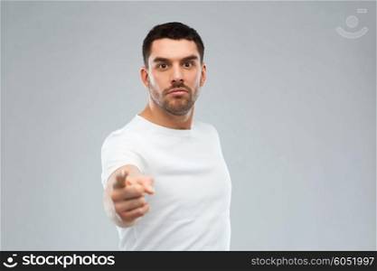 emotion, gesture and people concept - angry man pointing finger to you over gray background