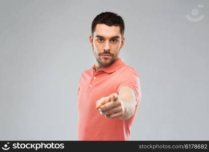 emotion, gesture and people concept - angry man pointing finger to you over gray background