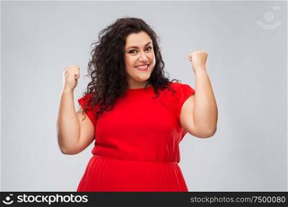 emotion, gesture and success concept - happy woman in red dress and making fist pump over grey background. happy woman in red dress celebrating success
