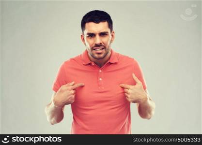emotion, gesture, argue and people concept - arguing angry man pointing finger to himself over gray. angry man pointing finger to himself over gray