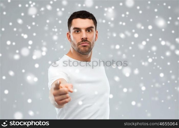 emotion, gesture, winter, christmas and people concept - angry man pointing finger to you over snow on gray background