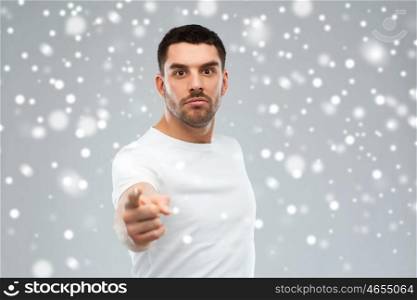 emotion, gesture, winter, christmas and people concept - angry man pointing finger to you over snow on gray background