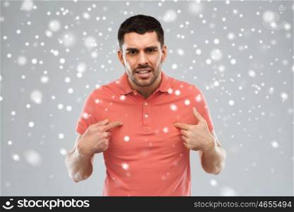 emotion, gesture, winter, christmas and people concept - arguing angry man pointing finger to himself over snow on gray background