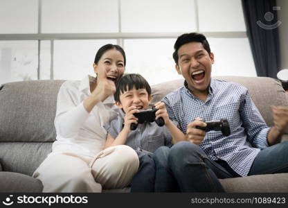 emotion of young family, father, mother and son watching TV and playing game together in living room, happy family concept