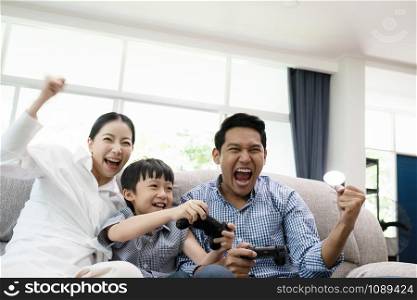 emotion of young family, father, mother and son watching TV and playing game together in living room, happy family concept