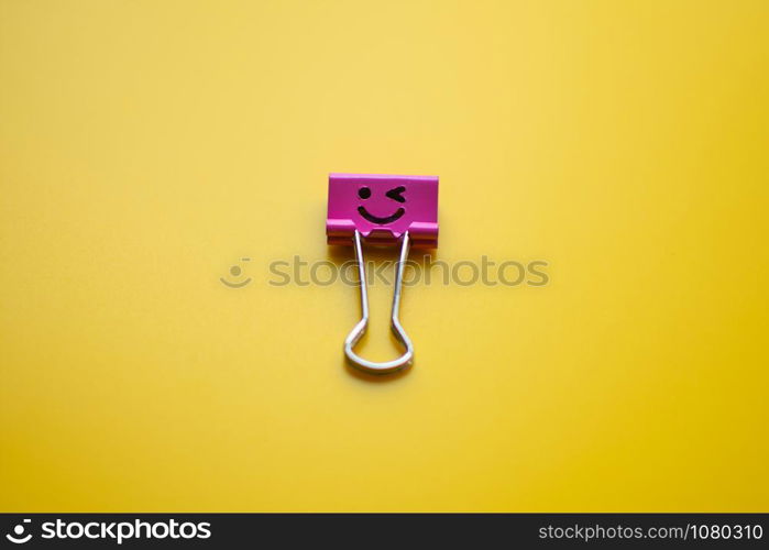 emotion on paper clip on yellow background. subject is blurry.