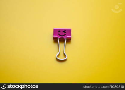 emotion on paper clip on yellow background. subject is blurry.