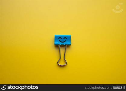 emotion on paper clip on yellow background. subject is blurry.