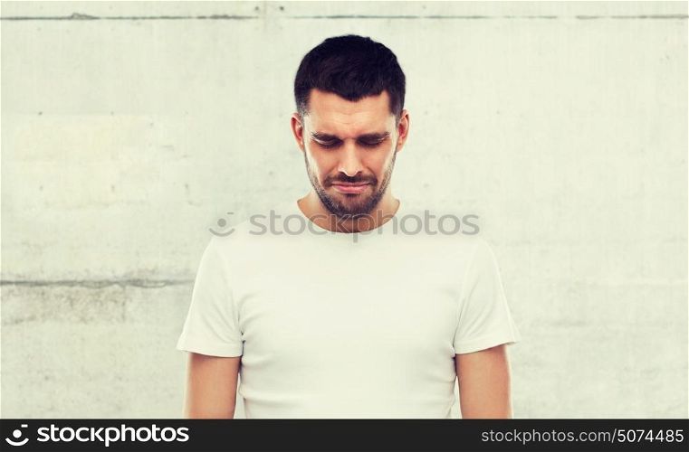 emotion, sadness and people concept - unhappy young man over gray wall background. unhappy young man over gray wall background