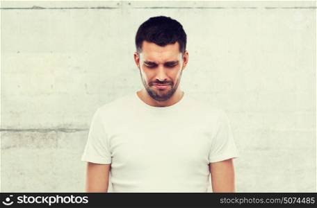 emotion, sadness and people concept - unhappy young man over gray wall background. unhappy young man over gray wall background
