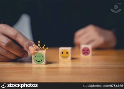 Emotion smiley face selected by a businessman’s hand on a wooden cube represents the best customer experience. Satisfaction survey and feedback concept. 5-star satisfaction is guaranteed.. 5-star satisfaction is guaranteed with a smiley face selected by a businessman