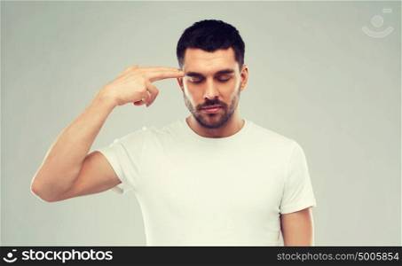 emotion, stress and people concept - man making finger gun gesture over gray background. man making finger gun gesture over gray background