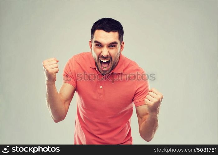 emotion, success, gesture and people concept - happy young man celebrating victory over gray background. happy man celebrating victory over gray background